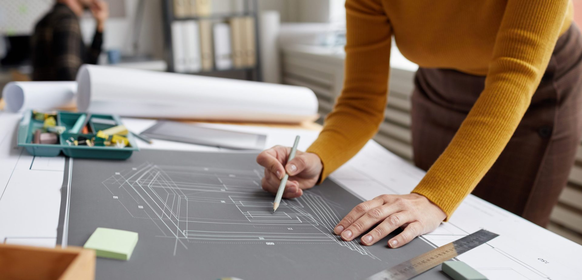 Cropped shot of unrecognizable female architect drawing blueprints and plans while working at desk in office, copy space